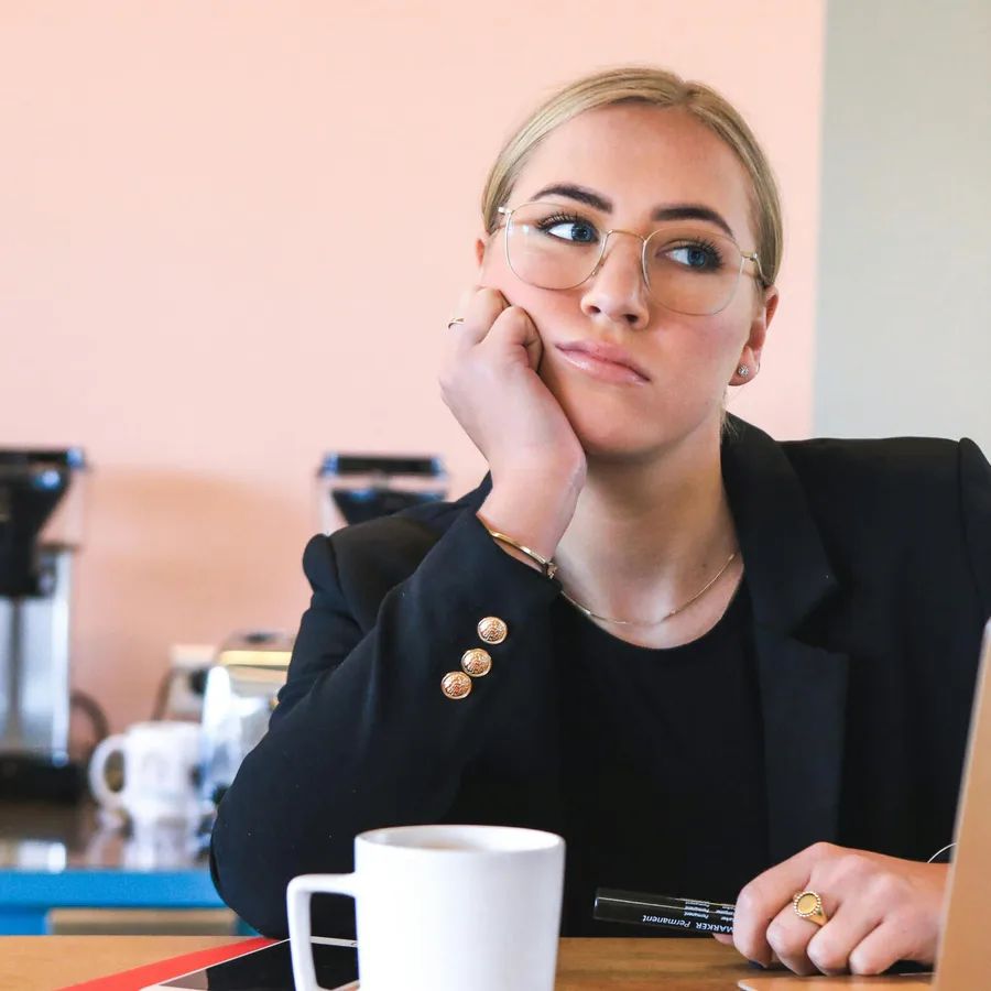 A woman looking distracted and disengaged at her desk
